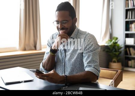 Smiling biracial man have fun texting on cell Stock Photo