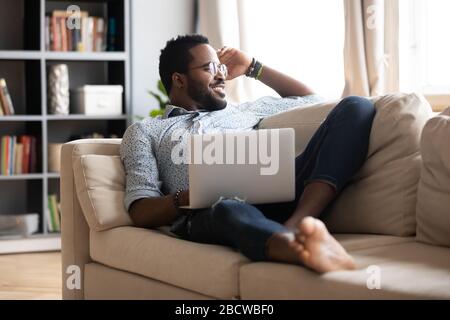 Smiling biracial male rest at home working in laptop Stock Photo