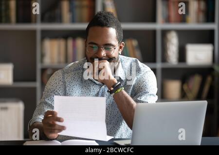 Pensive african American man reading letter in office Stock Photo