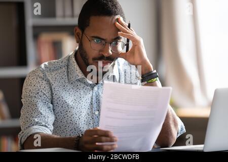 Unhappy african American man frustrated by bad letter Stock Photo
