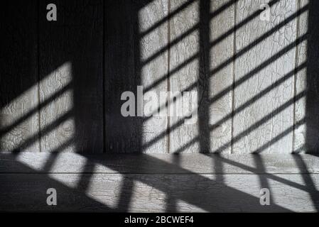 Graphic abstract shadow lines on dark wooden surface. Stock Photo