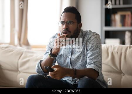 Anxious african American man watching television at home Stock Photo
