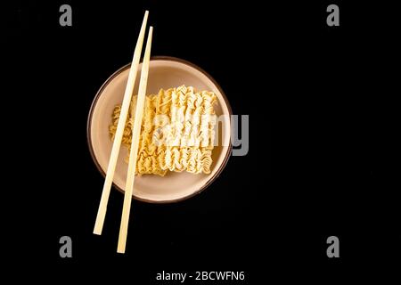 Instant noodles with wood sticks. Asian fast food on a black background close-up. Top views Stock Photo