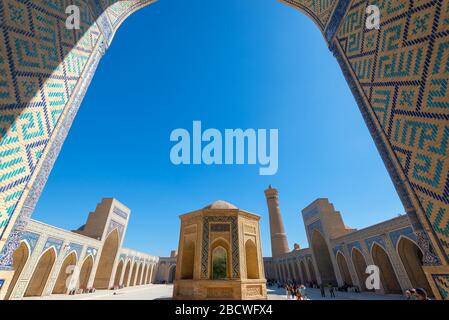 Po-i-Kalyan Complex featuring Kalan Mosque and Great Minaret of the Kalon in Bukhara, Uzbekistan. Blue and cyan mosaic tiles visible. Stock Photo