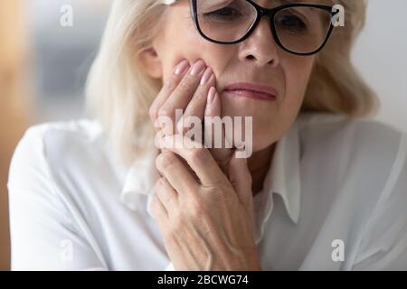 Close up 60 years old unhappy businesswoman having toothache. Stock Photo