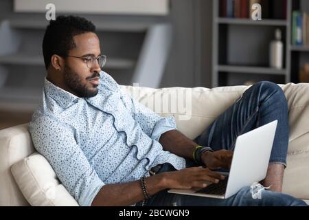 Focused biracial man busy working on laptop gadget Stock Photo