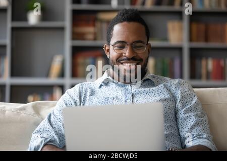Smiling biracial male working on modern laptop at home Stock Photo