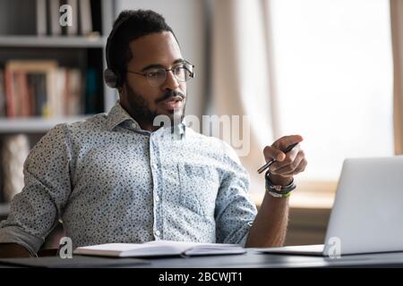 Focused biracial man in headphones busy working at workplace Stock Photo