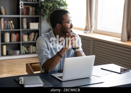 Happy biracial man look in distance dreaming at workplace Stock Photo