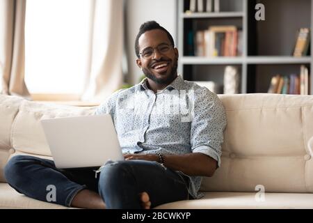 Portrait of happy biracial man working on laptop at home Stock Photo