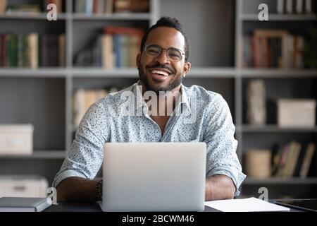 Portrait of smiling biracial man working on laptop Stock Photo
