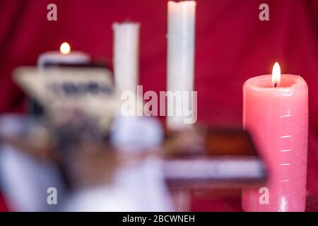 PINK CANDLE OF JESUS CHRIST ON THE CROSS WITH A RED TABLECLOTH Stock Photo