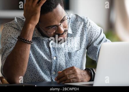 Frustrated african American man experience problems working on laptop Stock Photo