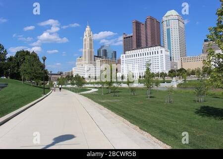 Alexander park Downtown Columbus Ohio green landscape with green trees, concrete walk way , colorful trees city skyline structure ,blue sky Stock Photo