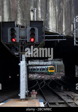 West Midlands Railway class 323 323243 arriving at Birmingham New Street with a cross city line train passing a red railway signal Stock Photo