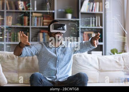 Excited biracial man in VR glasses have fun at home Stock Photo