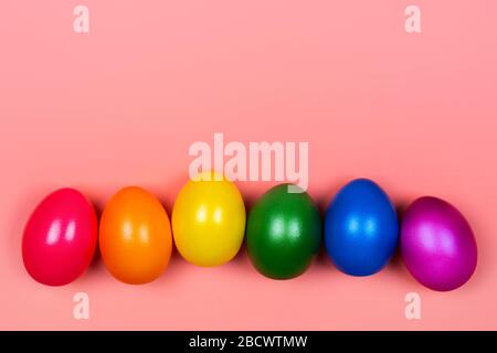 Different colorful eggs in neon trendy colors on coral background. Easter concept. Flat lay style. Stock Photo