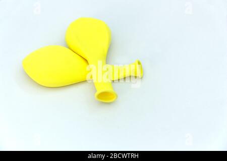 A few deflated yellow balloons that are one on another on a white table and space for texts Stock Photo