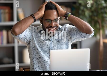 Overjoyed biracial man read good news online Stock Photo