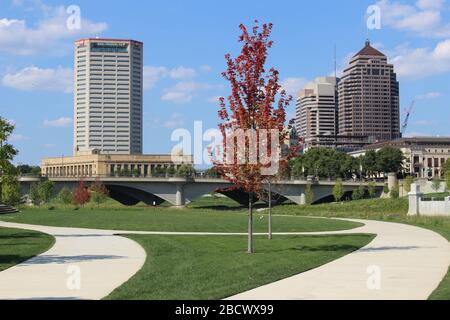 Alexander park Downtown Columbus Ohio green landscape with green trees, concrete walk way , colorful trees city skyline structure ,blue sky Stock Photo