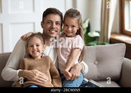 Smiling dad uncle holding on lap little children, portrait. Stock Photo