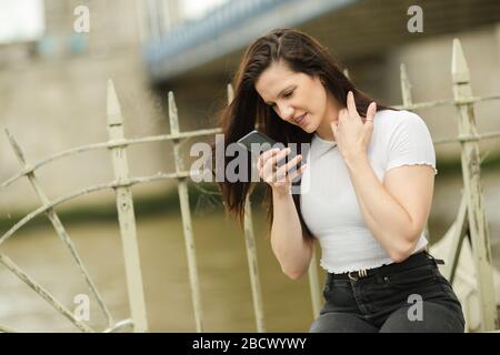 a young woman looking closely at her pone Stock Photo
