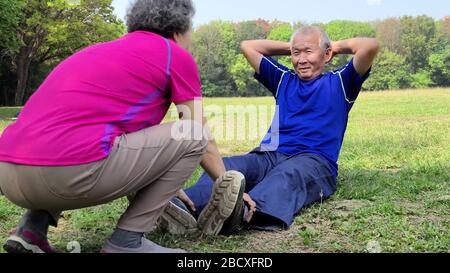 smiling senior grandfather doing sit-ups in the park Stock Photo