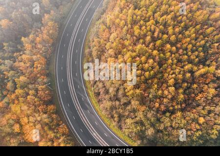 Aerial View over Dual Lane Road Across Autumnal Trees Stock Photo
