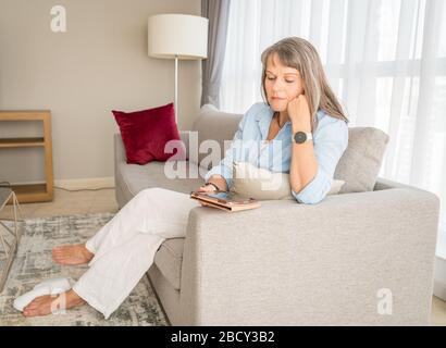 Mature woman looking at a tablet screen in her urban apartment Stock Photo
