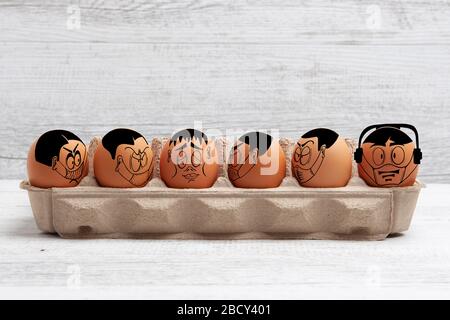 Self isolation and social distancing during Easter concept depicted with cartoon faces drawn on easter eggs with copy space Stock Photo