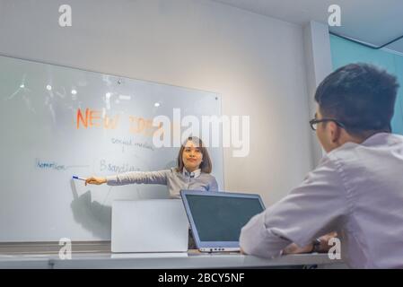 Woman making presentation and pointing at white board during meeting Stock Photo