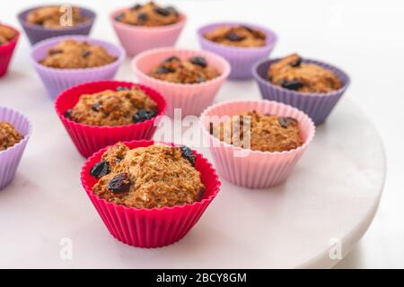 Bran muffins with dry cranberries close up in baking silicon cups on white background. Healthy food, good source of dietary fiber Stock Photo