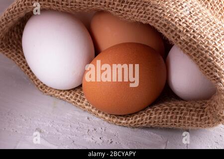 raw eggs from farm in eco sackcloth on wooden background, zero waste concept Stock Photo