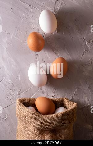 Chicken white and brown eggs in eco sackcloth burlap bag, zero waste concept. Flat lay Stock Photo