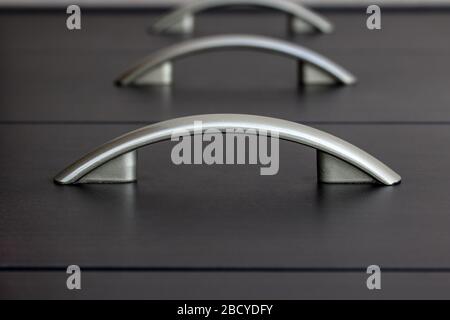 Close-up top view of drawers. Row of black drawers with arched handles in perspective view from above. Stock Photo