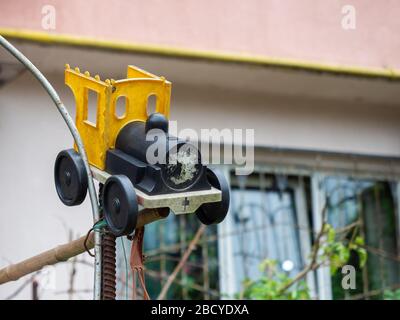 Plastic yellow black old toy car tied to metal bars on a blurred background Stock Photo