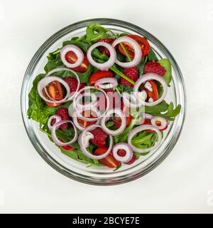 Fresh vegetable salad plate. Ingredients: green spring mix, cherry tomatoes, raspberries, onion, feta cheese, dressing. Step 4 - onion. Stock Photo
