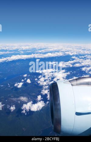 View from airplane window showing plane engine over the clouds. Vertical orientation. Stock Photo