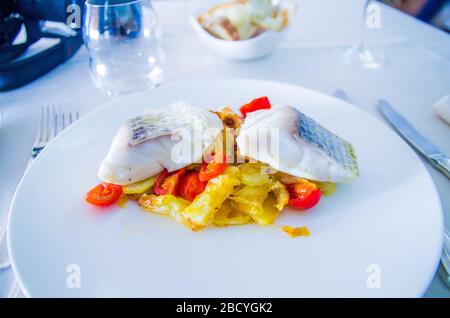 baked sea bass with fried vegetables and cherry tomatoes sautéed with aromatic herbs Stock Photo
