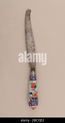 Knife. Research in ProgressSabre-shaped blade, silver ferrule with horizontal bands. Tapering porcelain handle, floral decoration in blue (underglaze), red and gold on a white ground. Silver button cap at the top of the handle. Knife Stock Photo