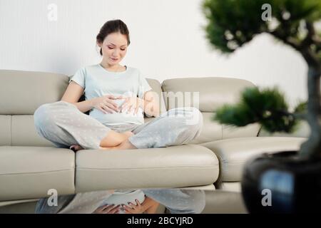 Happy young pregnant woman touching her belly and feeling baby kicking Stock Photo