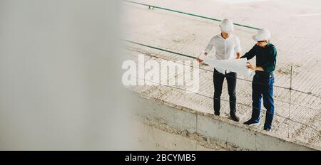 Caucasian men working with a new project posing with helmet on the newly constructed area Stock Photo