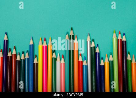 Colorful multicolor pencils arranged in a wave over blue background Stock Photo