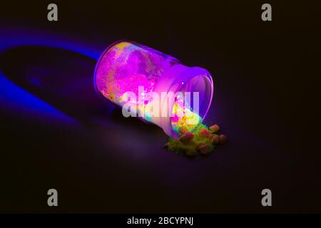 Photoluminescence chemical materials, called fluorescent. Powder glows in the dark under UV light radiation of different colors. For OLED displays man Stock Photo