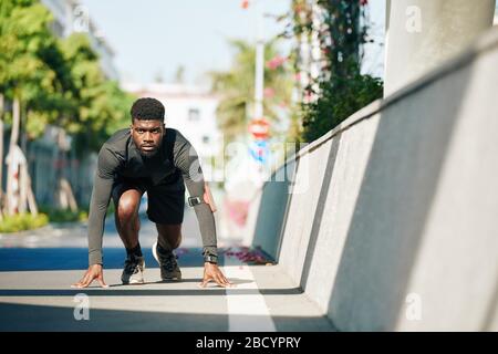 Serious determined young sportsman ready to run sprint or marathon Stock Photo