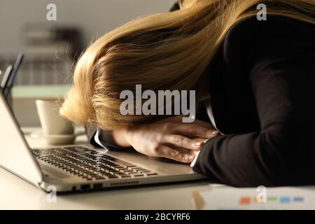 Close up of tired overworked business woman sleeping over laptop on a desk at night in the office Stock Photo