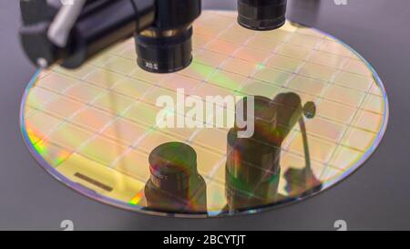 Close up of silicon wafer with microchips on machine process examining in microscope and checking quality . Selective focus. Stock Photo