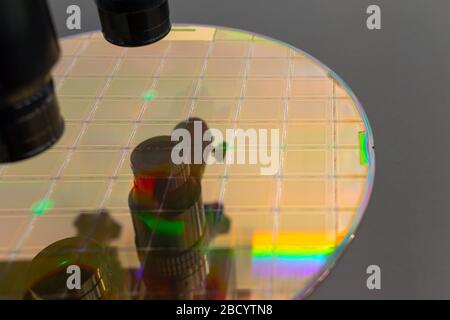 Close up of silicon wafer with microchips on machine process examining in microscope and checking quality . Selective focus. Stock Photo