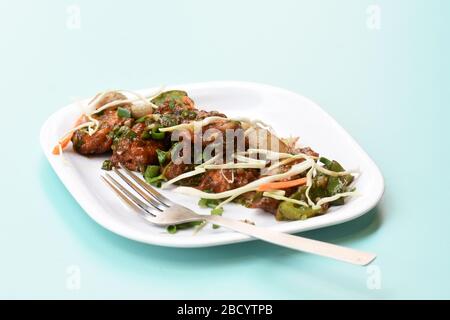 chilli paneer or Spicy cottage cheese, Garnish with capsicum, onion,cabbage and spring onion, favourite indian starter menu, served in white Dish Stock Photo