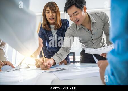 Group of Asian business people are working and brainstorming together over the document paper of project planning in office meeting room, Business mee Stock Photo